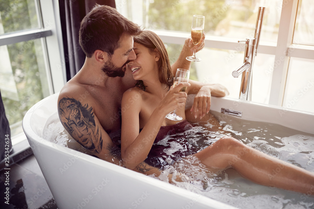 Obraz premium beautiful couple drinking champagne in the bathtub.