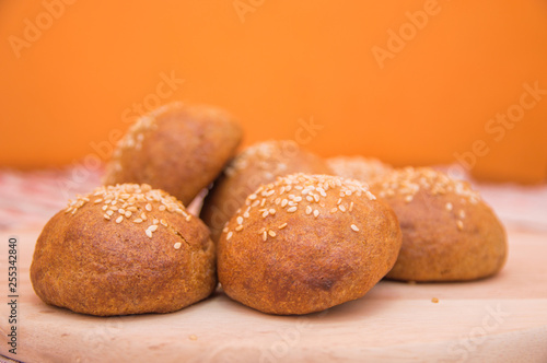 Tasty buns with sesame, on wooden background