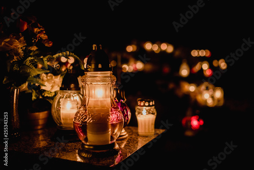 The cemetery, candles burning in lanterns at night during All Saints Day, bokeh of light candle.