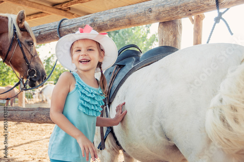 Little cheerful girl and the horse. Girl in a hat.