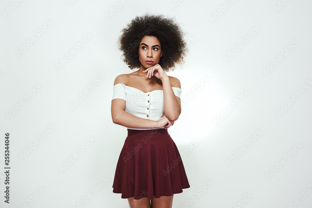 What should i do? Thoughtful afro american woman is holding hand on her chin, thinking and looking away while standing against grey background What should i do? Thoughtful afro american woman is holding hand on her chin, thinking and looking away while standing against grey background