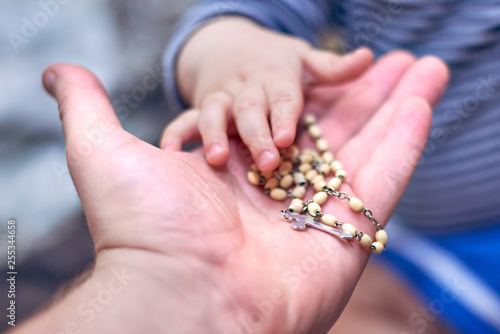 A child takes a rosary from his dad's hand photo