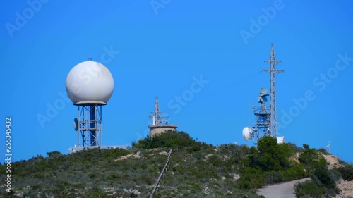 A meteorological radar with a large white sphere on top of a mountain collects weather data from the whole area. Shot in motion
