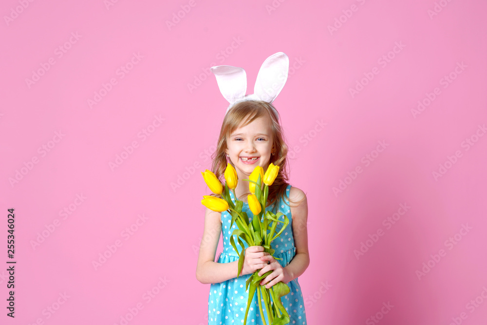 Cute little girl in the form of an Easter Bunny with a bouquet of yellow tulips. concept of holidays, fashion and beauty. Happy Easter! Selective focus.