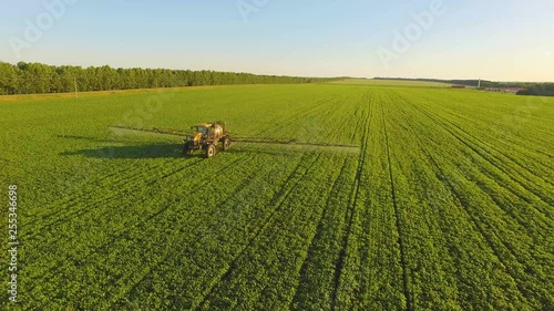 Tractor spraying pesticides on soybean field with sprayer at spring. Aerial Quadcopter Shooting
