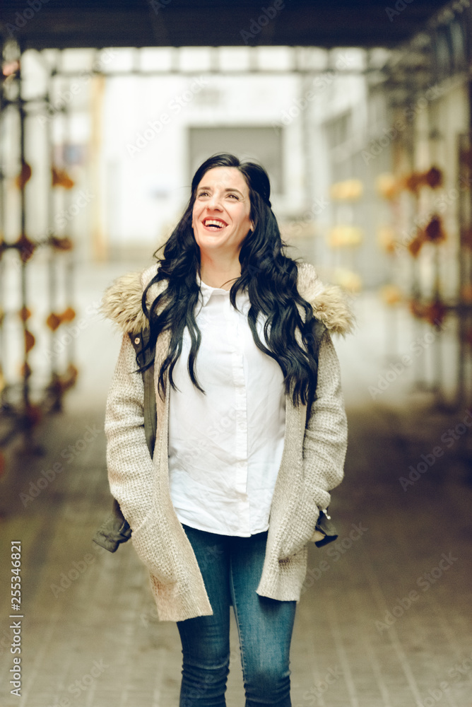 Fototapeta premium Middle-aged woman smiling and laughing happily walking through the city.