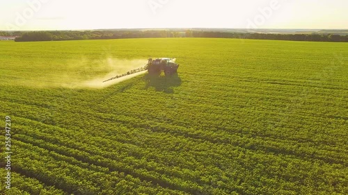 Tractor spraying pesticides on soybean field with sprayer at spring. Aerial Quadcopter Shooting