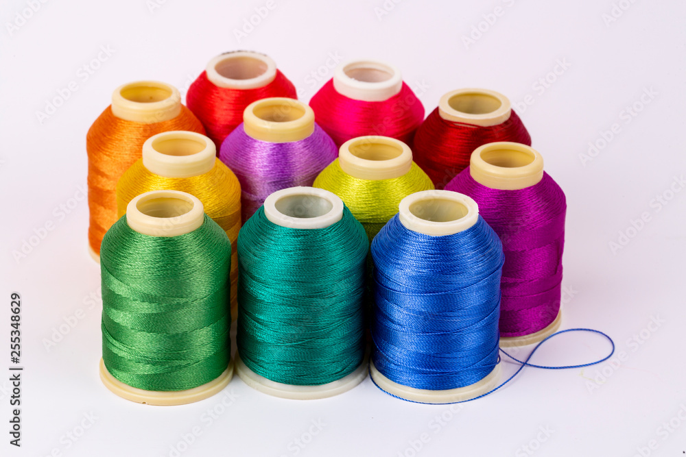 Colored thread coils on white background, sewing, place for text Colored thread coils on white background, sewing, place for text