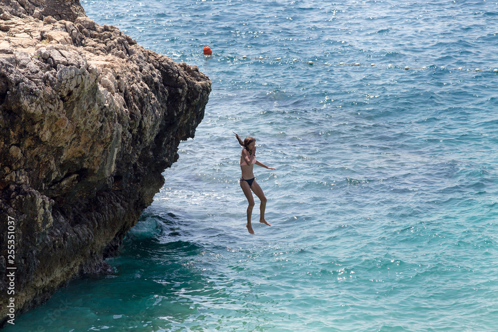 Girl jumping in water from cliff