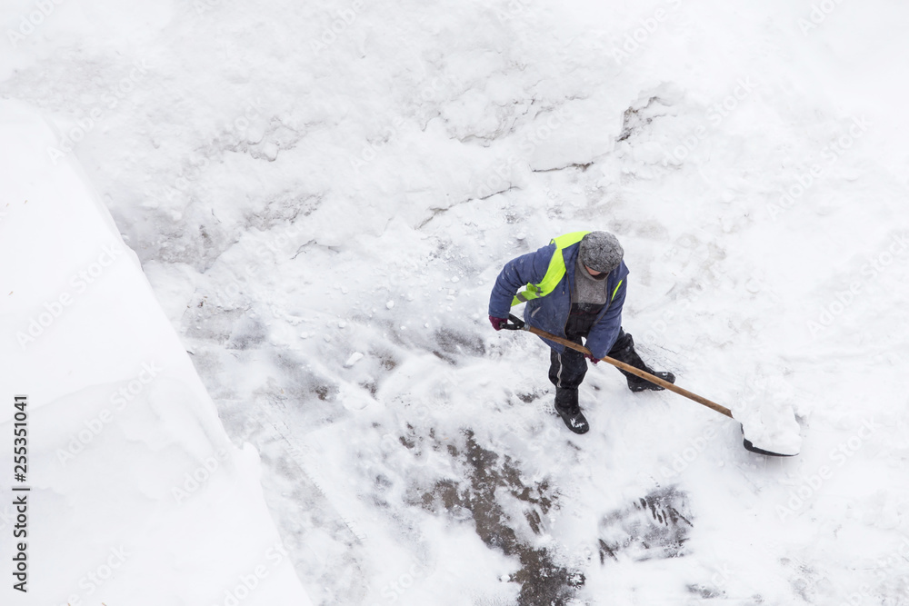 Man shoveling snow after snowfall and blizzard, copy space. Top view of snow clearance