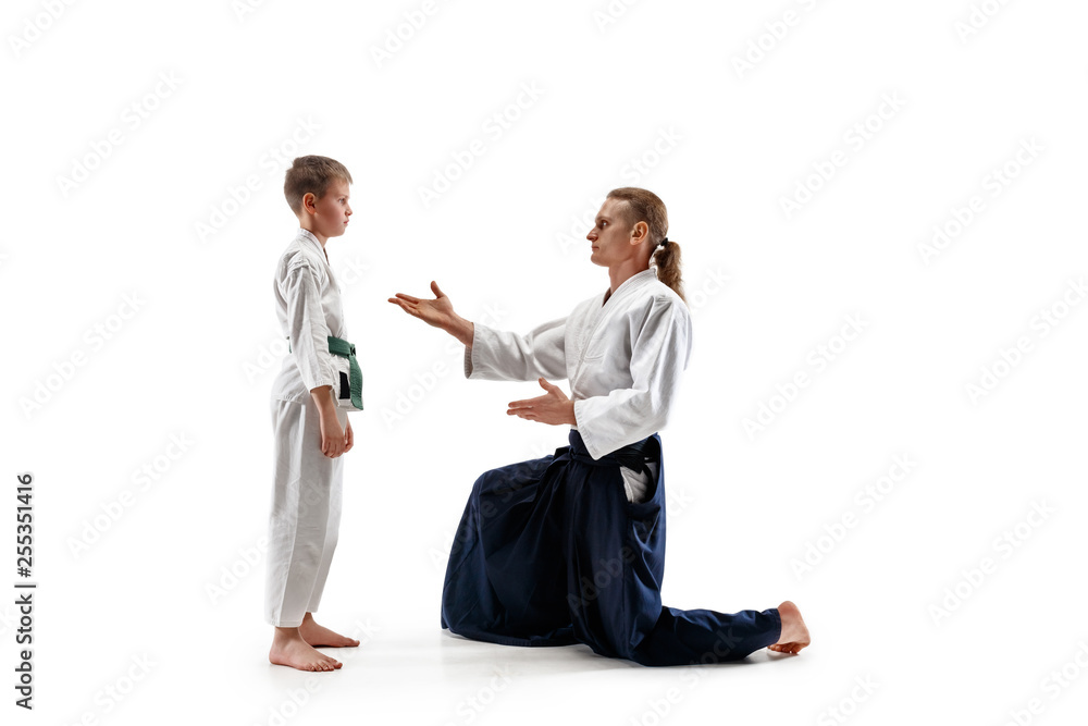 Man and teen boy fighting at Aikido training in martial arts school. Healthy lifestyle and sports concept. Fightrers in white kimono on white background. Karate men with concentrated faces in uniform. Man and teen boy fighting at Aikido training in martial arts school. Healthy lifestyle and sports concept. Fightrers in white kimono on white background. Karate men with concentrated faces in uniform.
