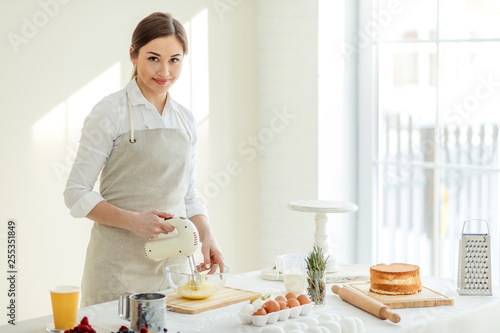Young gorgeous woman posing to the camera while cooking cake. close up photo. copy space.occupation