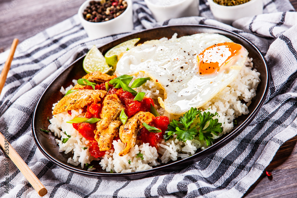 Grilled chicken meat with rice and fried egg on wooden table Grilled chicken meat with rice and fried egg on wooden table