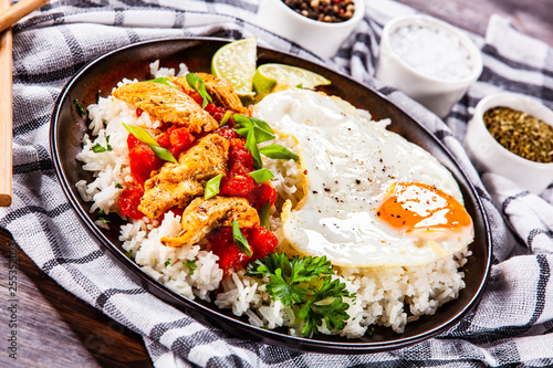 Grilled chicken meat with rice and fried egg on wooden table