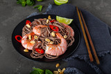 Stir fry noodles with vegetables and shrimps in black bowl.