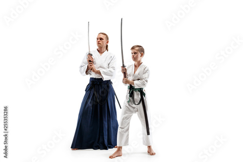 Man and teen boy fighting at Aikido training in martial arts school. Healthy lifestyle and sports concept. Fightrers in white kimono on white background. Karate men with concentrated faces in uniform.