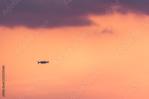 Drone with remote control. Dark silhouette against colorful sunset. Soft focus. Toned image
