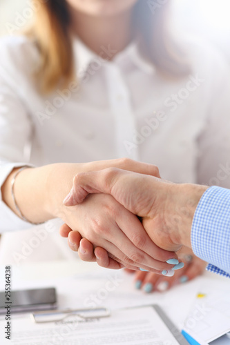 Businessman and woman shake hands as hello in office