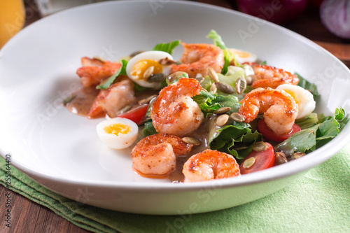 Healthy salad. Recipe for fresh seafood. Grilled shrimp, fresh vegetable salad and egg. Shrimp on the grill. Health food. Wooden background