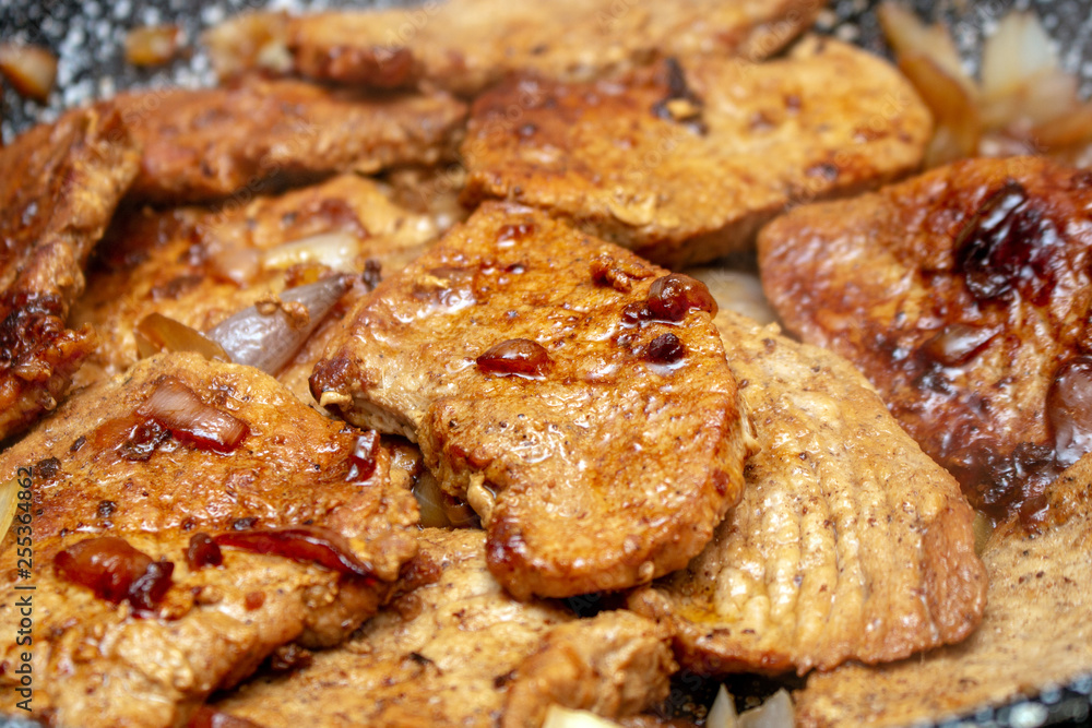 Cooking fryed meat on the pan with onion close up