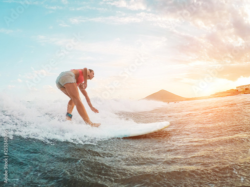 Canvas Print Female athlete surfing at sunset - Surfer woman performing outdoor inside ocean