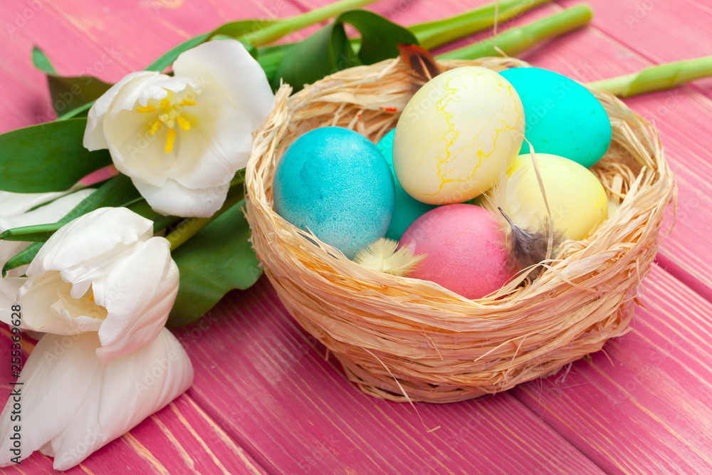 easter, holidays, tradition and object concept - close up of colored eggs and tulip flowers over wooden boards background