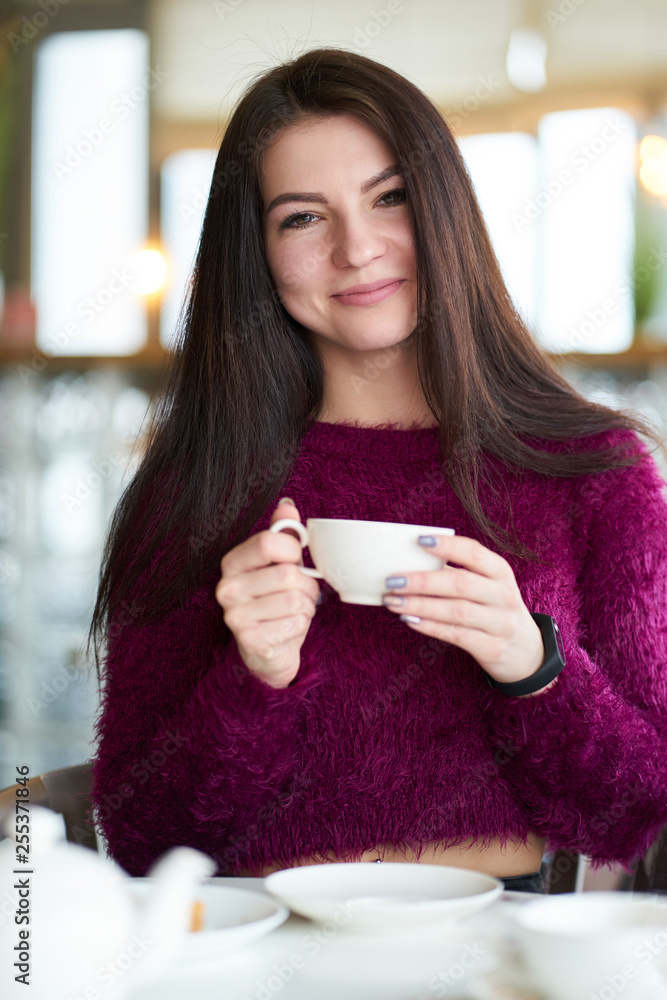 Young white brunette girl drinking tea in cafe and smiling Young white brunette girl drinking tea in cafe and smiling