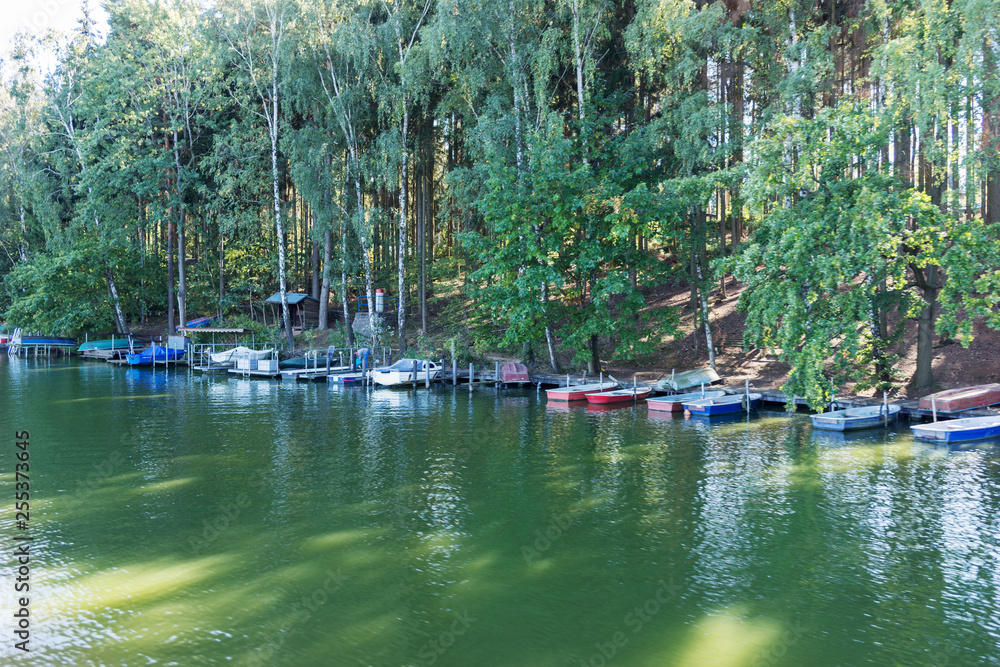 Small boats on the shore of the lake at the edge of the forest Small boats on the shore of the lake at the edge of the forest