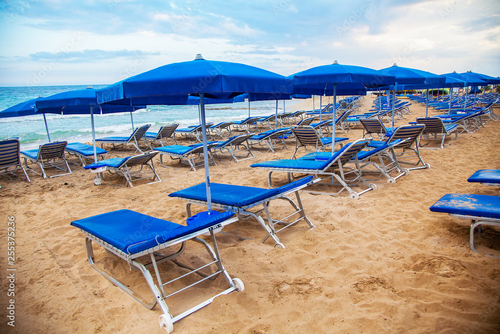 Blue empty sunbeds with umbrellas on the beach