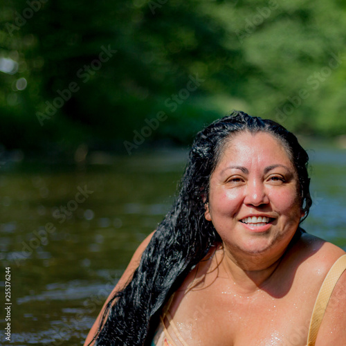 Beautiful tanned mexican woman with long black hair smiling on a wonderful sunny summer day with the river Ahr background in Schuld Germany