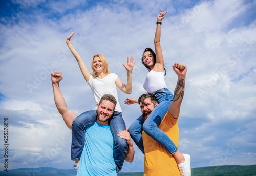 We are the winners. Happy men piggybacking their girlfriends. Loving couples enjoy fun together. Playful couples in love smiling on cloudy sky. Loving couples having fun activities outdoor