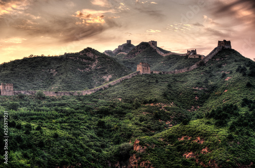 Great Wall of China and beautiful mountains covered by forest in dramatic light.