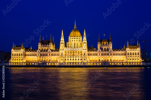 Illuminated Budapest parliament building at night with dark sky and reflection in Danube river