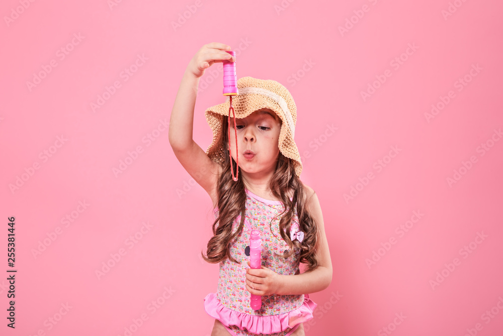 little girl blowing soap bubbles on colored background