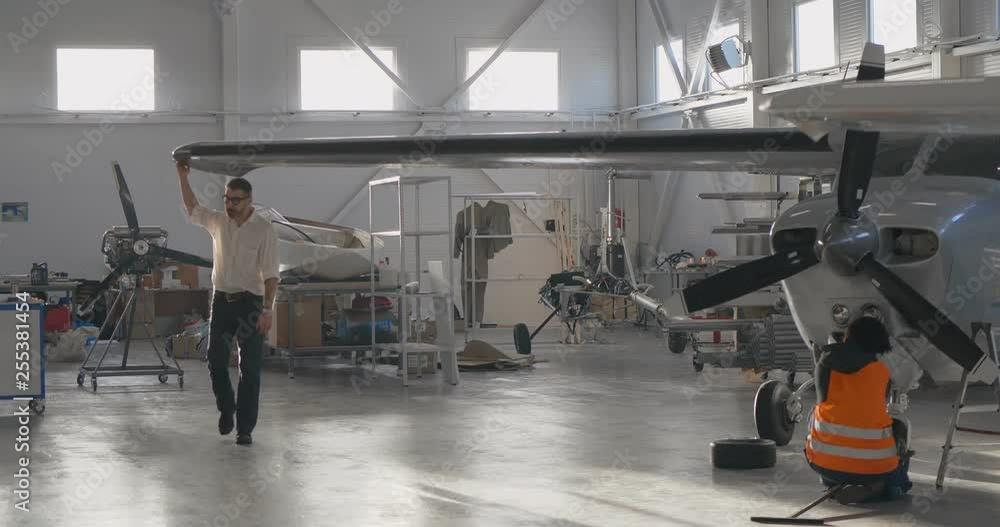 Caucasian aircraft engineer walking in hangar between airplanes Caucasian aircraft engineer walking in hangar between airplanes