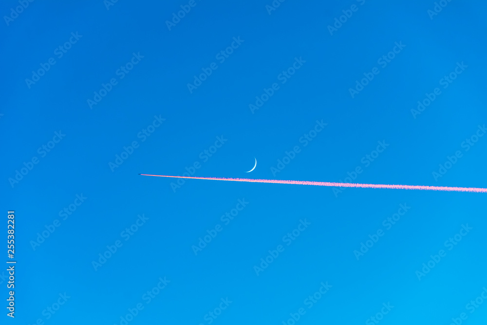 Airplane flying on blue sky with moon during sunset Airplane flying on blue sky with moon during sunset
