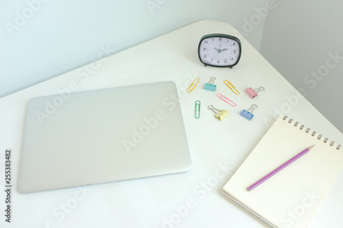 Laptop, stationery, office supplies on white modern home office desk workspace on pale blue and yellow pastel color background with copy space. Creative, freelance and minimal office. Retro interior.