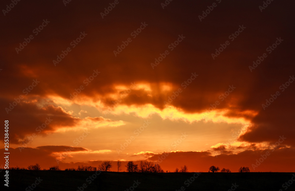 Landscape of colorful dramatic sky clouds in rays of sunset light, beautiful nature background