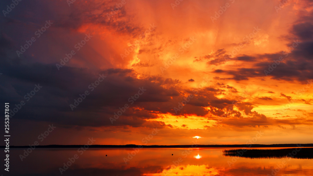 Stunning panorama of an unusually beautiful sunset with amazing sky over the lake on a warm summer day