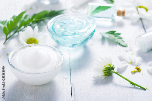 spa setting with cosmetic cream  gel  bath salt and fern leaves on white wooden table background