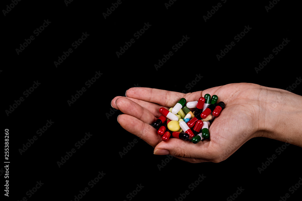 Female hand holding a lot of different colored capsules and pills Female hand holding a lot of different colored capsules and pills