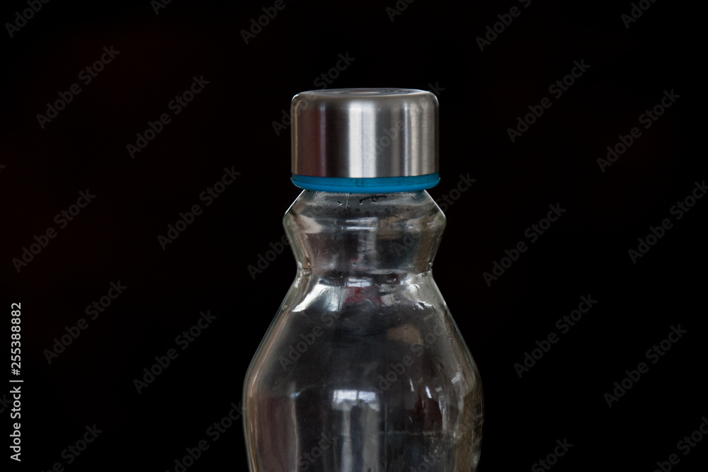An empty glass water bottle isolated against a black background image with copy space An empty glass water bottle isolated against a black background image with copy space