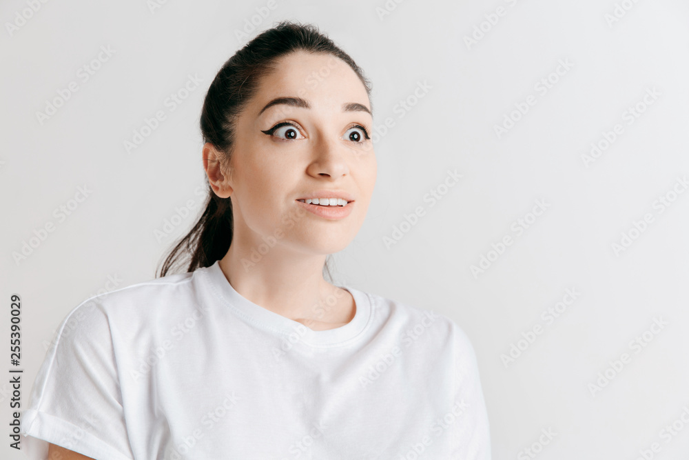 Wow. Beautiful female half-length front portrait isolated on gray studio backgroud. Young emotional surprised woman standing with open mouth. Human emotions, facial expression concept. Wow. Beautiful female half-length front portrait isolated on gray studio backgroud. Young emotional surprised woman standing with open mouth. Human emotions, facial expression concept.