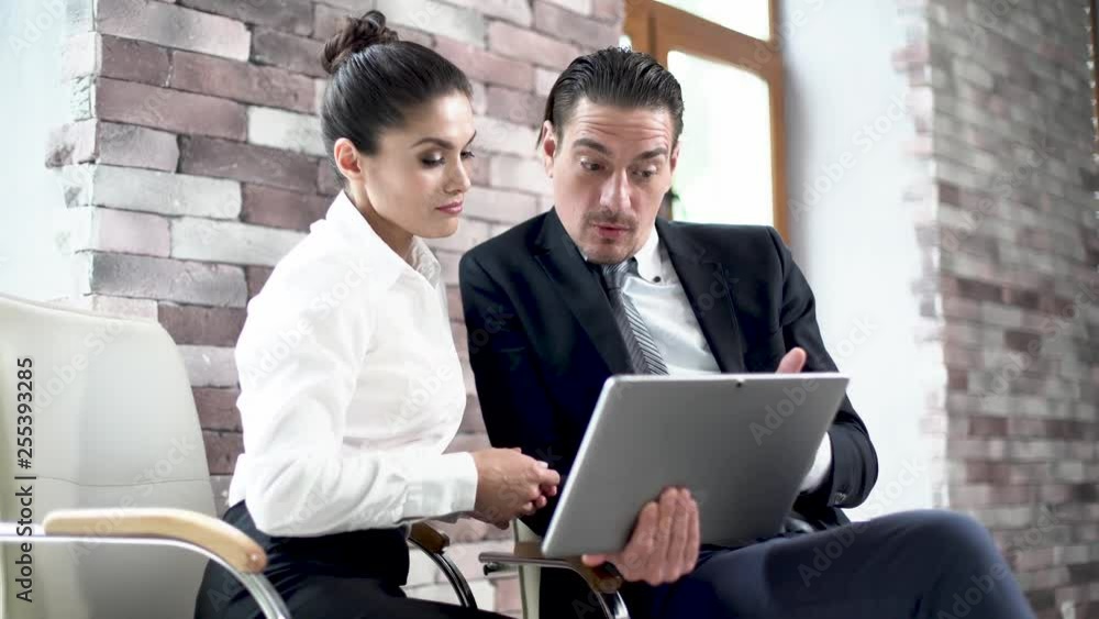 A Business Man And a Business Woman are Sitting in a Conference Room and are Looking at a New Project on a Map-Case. A Business Man And a Business Woman are Sitting in a Conference Room and are Looking at a New Project on a Map-Case.