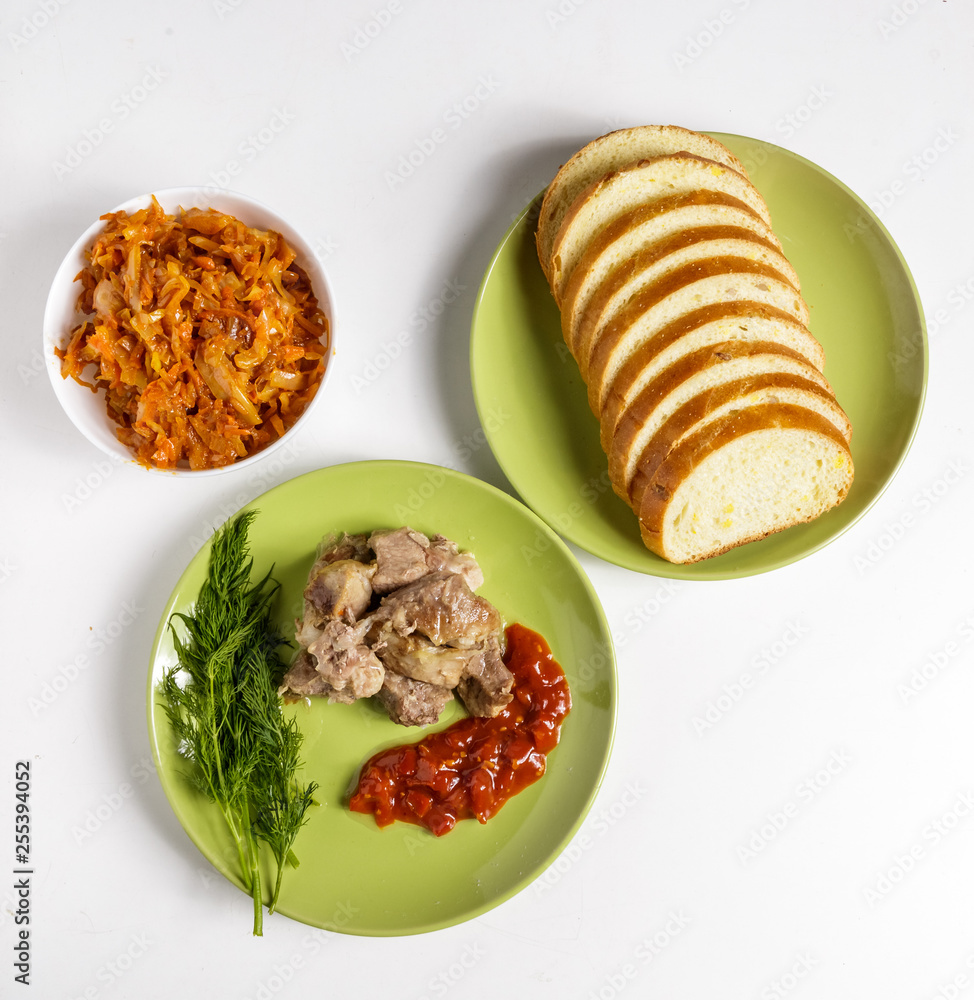 Pieces of roast meat, tomato sauce, dill bread and sauerkraut on a plate on a white background.