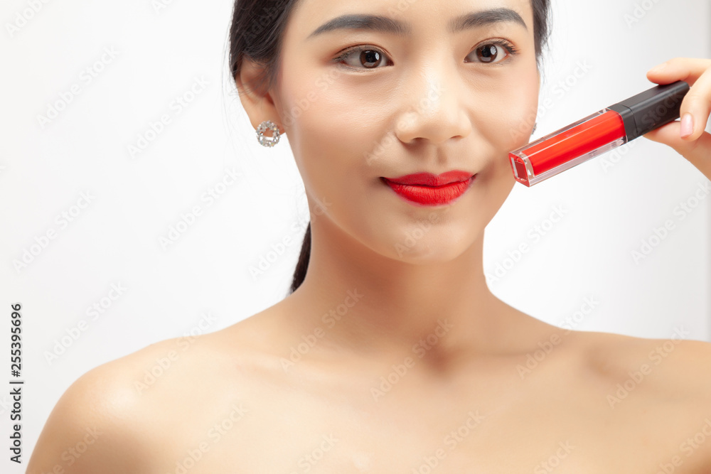 Young asian woman applying red lipstick on white background. Young asian woman applying red lipstick on white background.