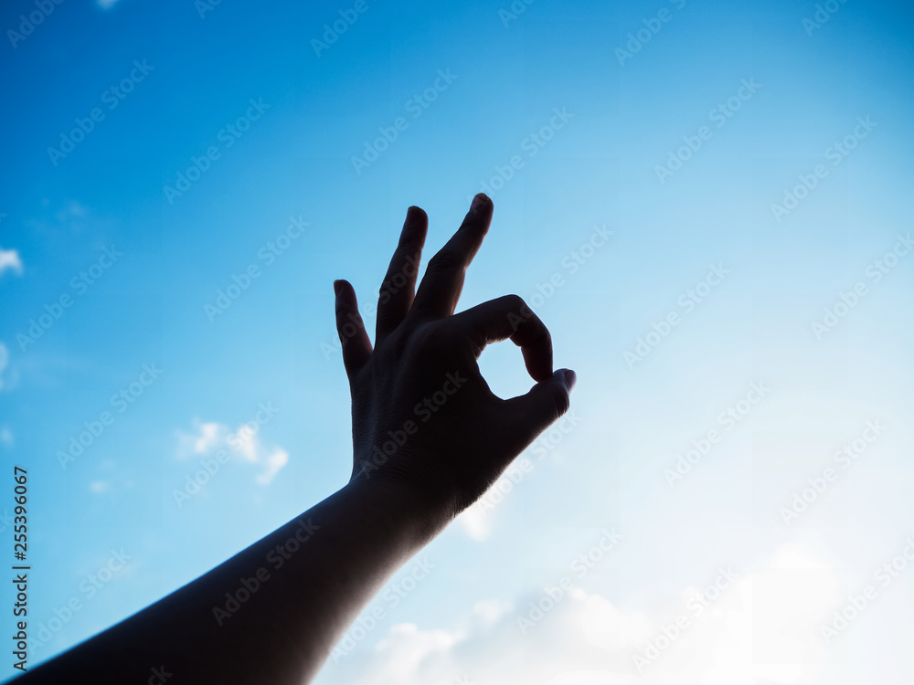 The silhouette hand sign reach to the sky background, finger touch together,symbol of success,positive sign The silhouette hand sign reach to the sky background, finger touch together,symbol of success,positive sign