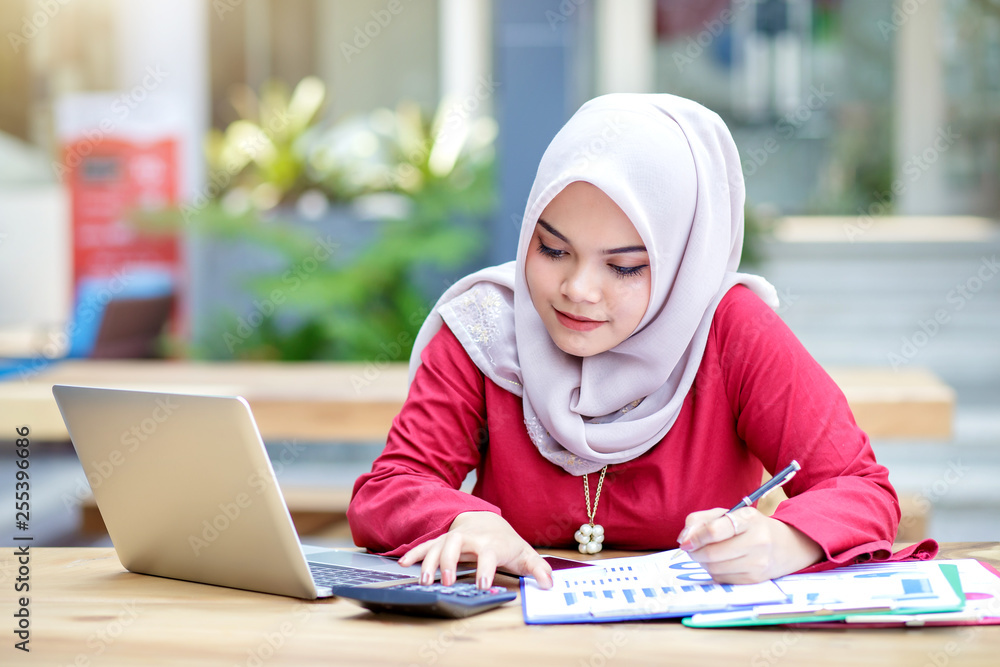 Young asian muslim woman working on laptop outdoor. Young asian muslim woman working on laptop outdoor.