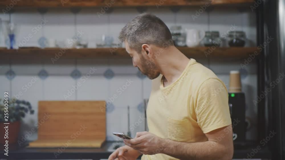 Handsome man in kitchen using smartphone Handsome man in kitchen using smartphone
