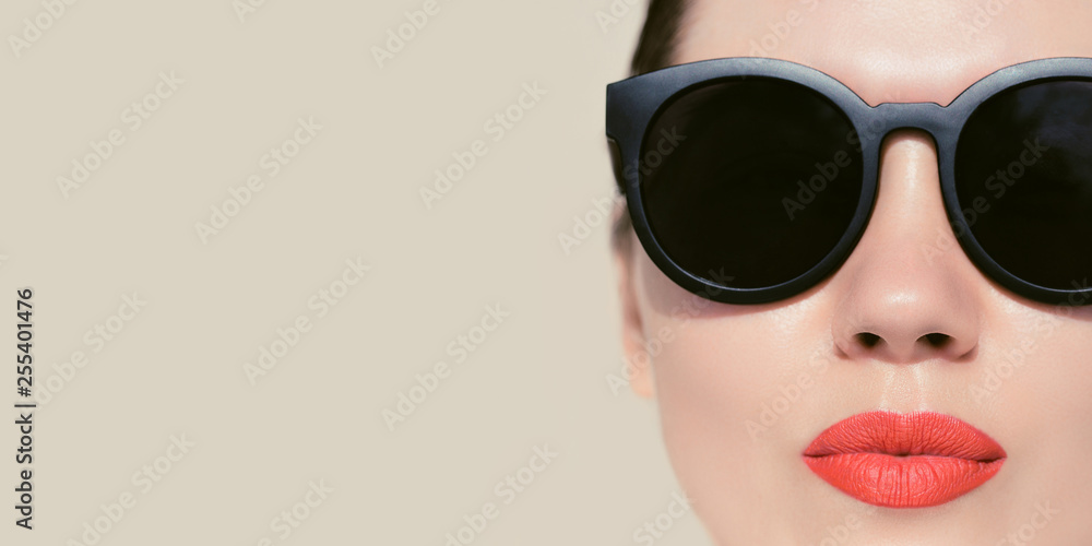 Portrait close up of a pretty woman with bright red painted lips and sunglasses on a beige background Portrait close up of a pretty woman with bright red painted lips and sunglasses on a beige background